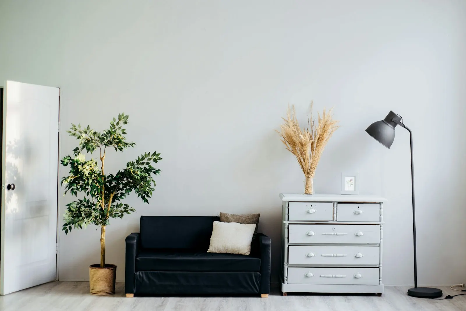 Living corner with charcoal accents, a pale dresser and cascading plants over soft neutrals
