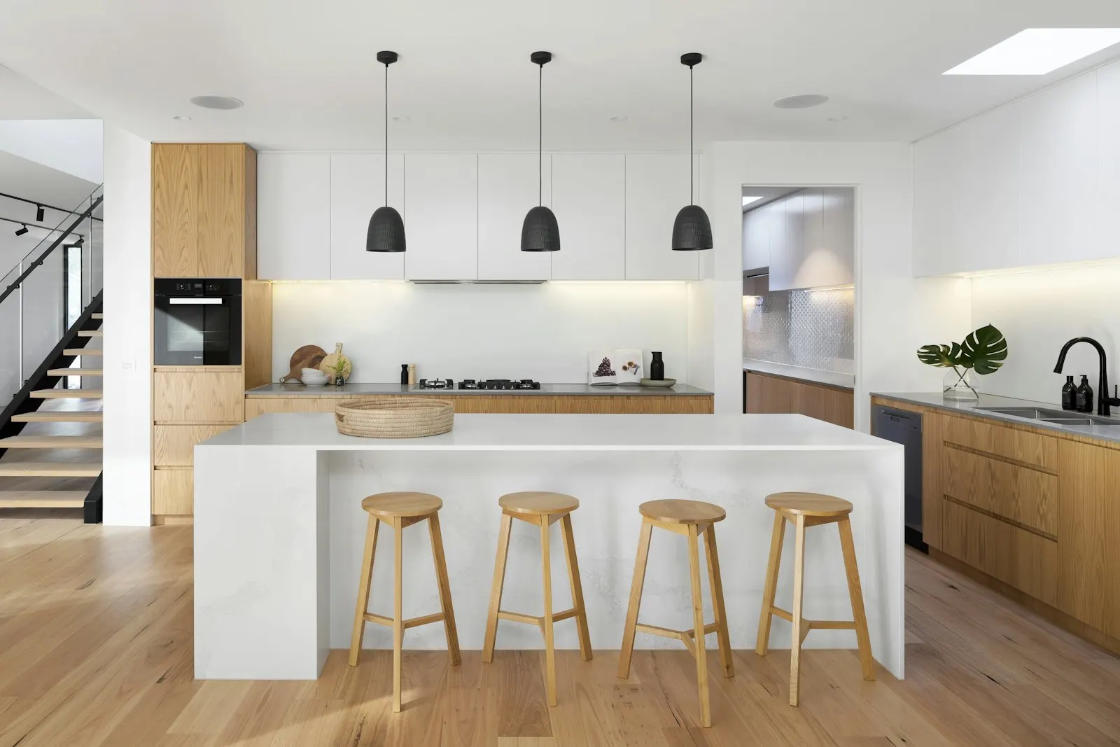 Kitchen island with bar stools, pendant lights and a stone backsplash